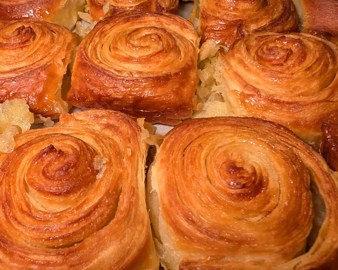 Close-up of golden, caramelized pastries with spiral layers, packed side by side